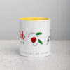 White ceramic coffee mug with yellow interior and red flower art.