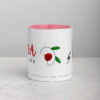 Pink-lined white coffee mug with red flower graphic.